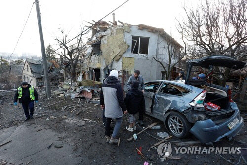 키이우 주민들이 31일(현지시간) 러시아의 공습으로 파괴된 시내 주거 건물과 자동차를 지켜보고 있다. [키이우 로이터=연합뉴스]